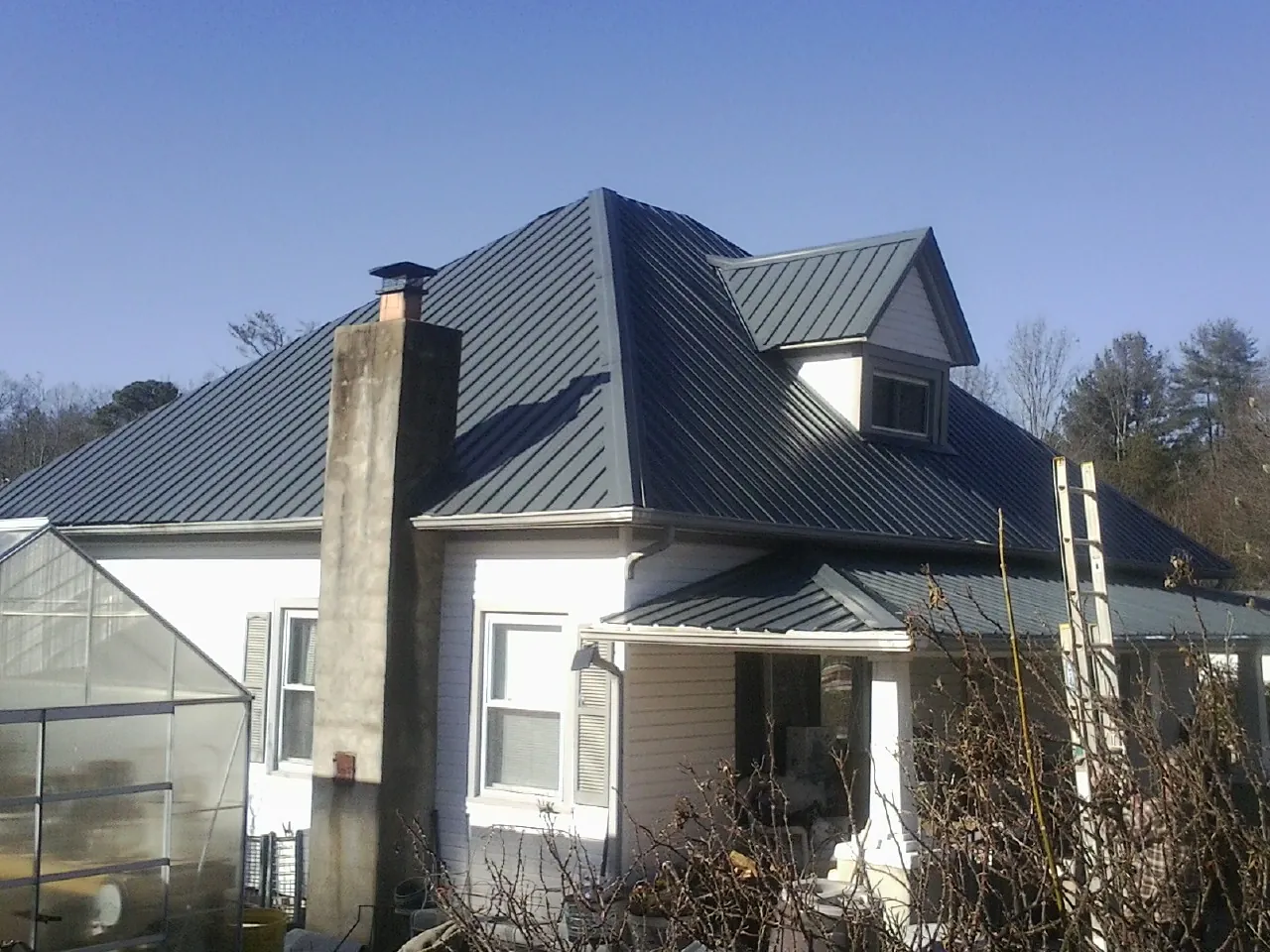 Dark blue standing seam metal roof on a white farmhouse with dormer — Slate & Tile Roof Repair by Roofing Brothers in Wyocena