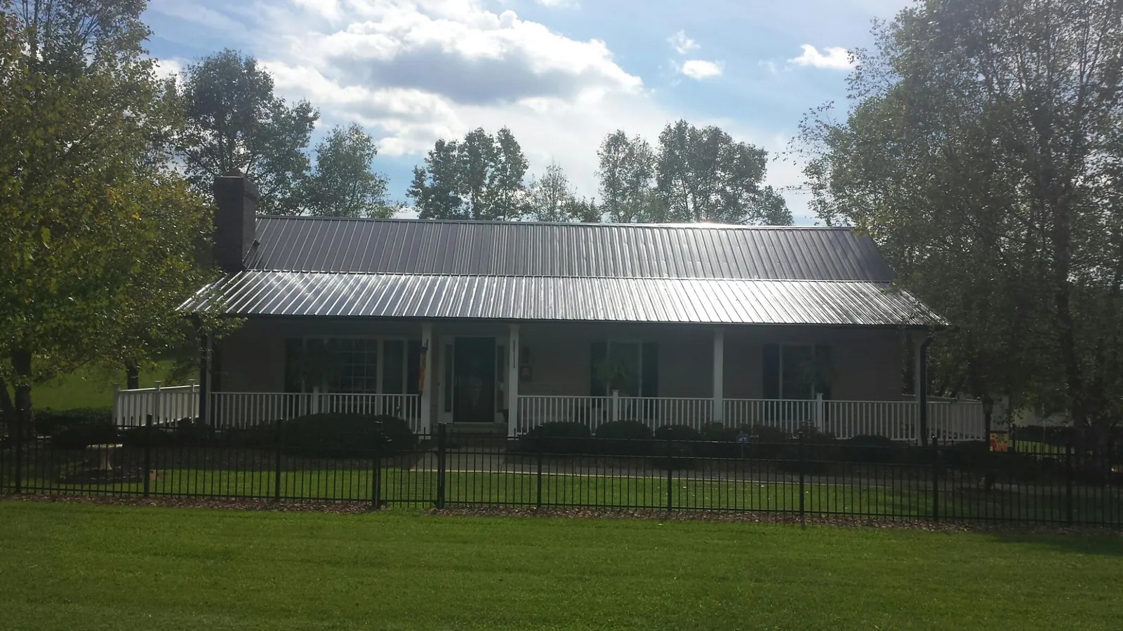 Gray metal roof on a brick ranch with a full width front porch — Gutter Guard Installation work by our crew in Wyocena