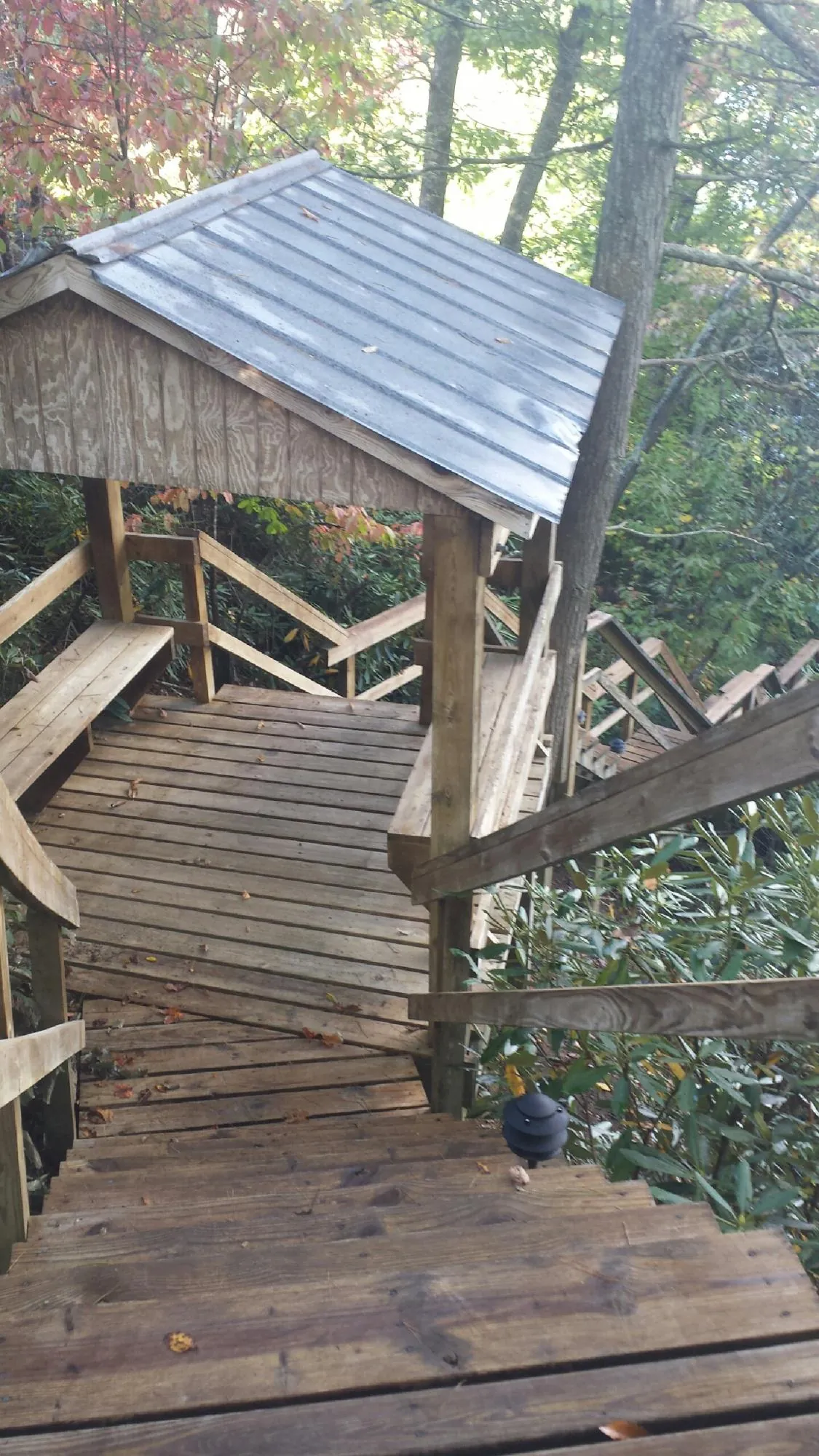 Metal roofed shelter over wooden steps on a wooded walkway — Skylight Repair & Installation work by our crew in Wyocena