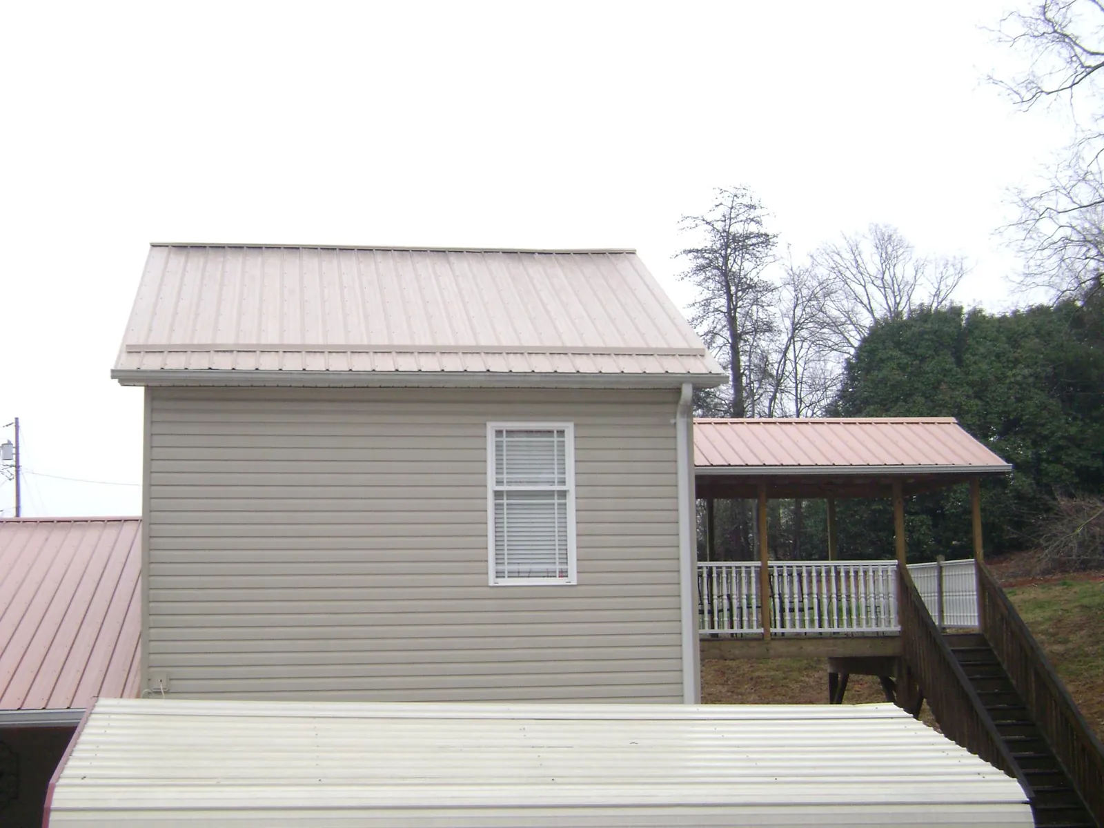 Tan metal roofs on a two story addition and attached porch, from a Roof Replacement job in Wyocena