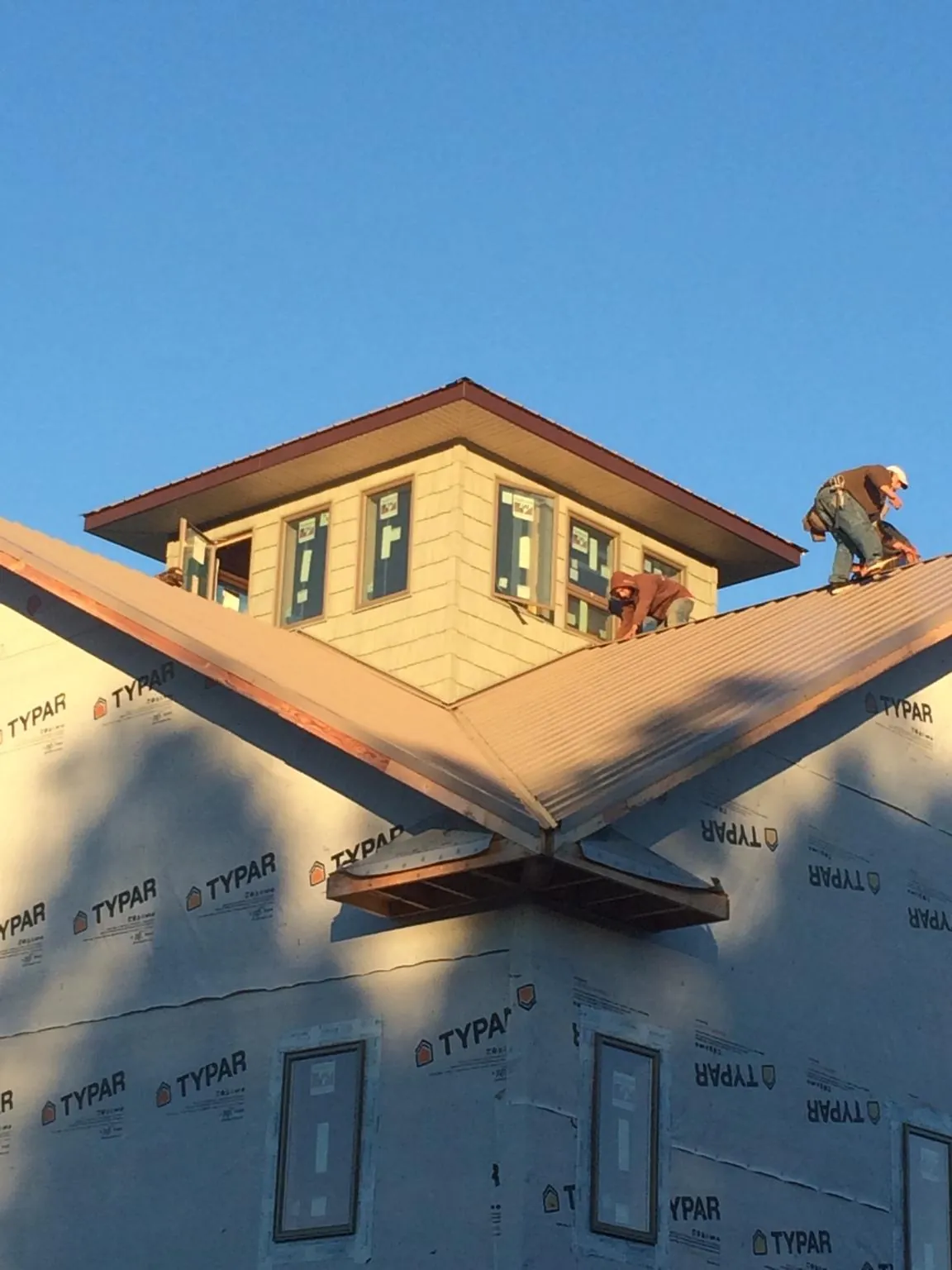Roofers working around a rooftop cupola on a new metal roof at sunset — Roof Waterproofing in Wyocena by Roofing Brothers